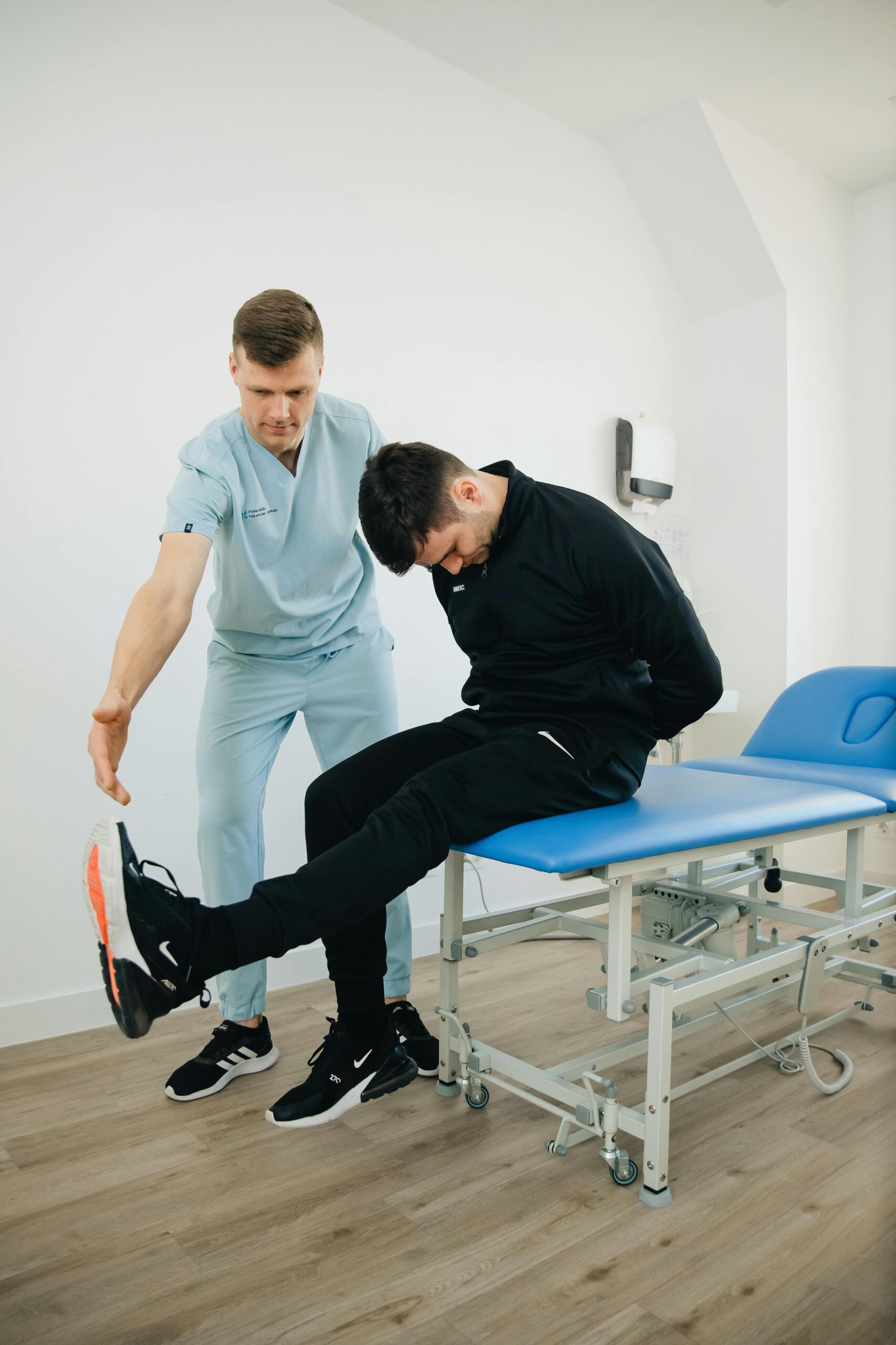 Physiotherapist assisting a man with rehabilitation exercises on a treatment table in a clinic.