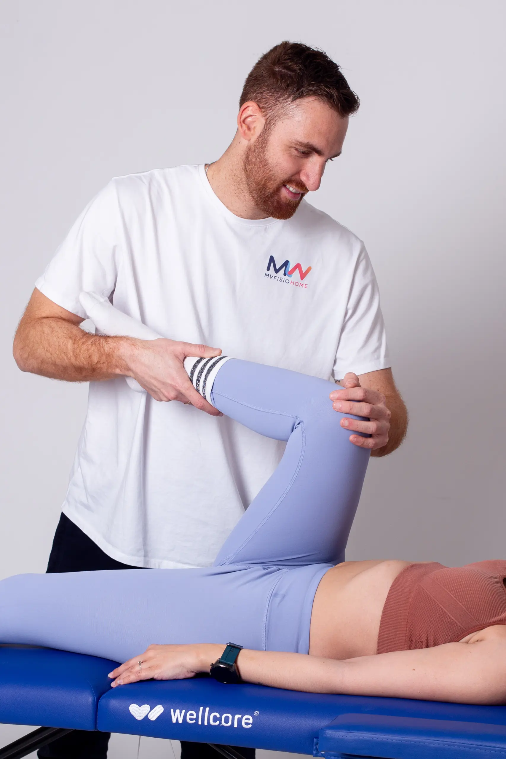 Physiotherapist assisting a man with rehabilitation exercises on a treatment table in a clinic.