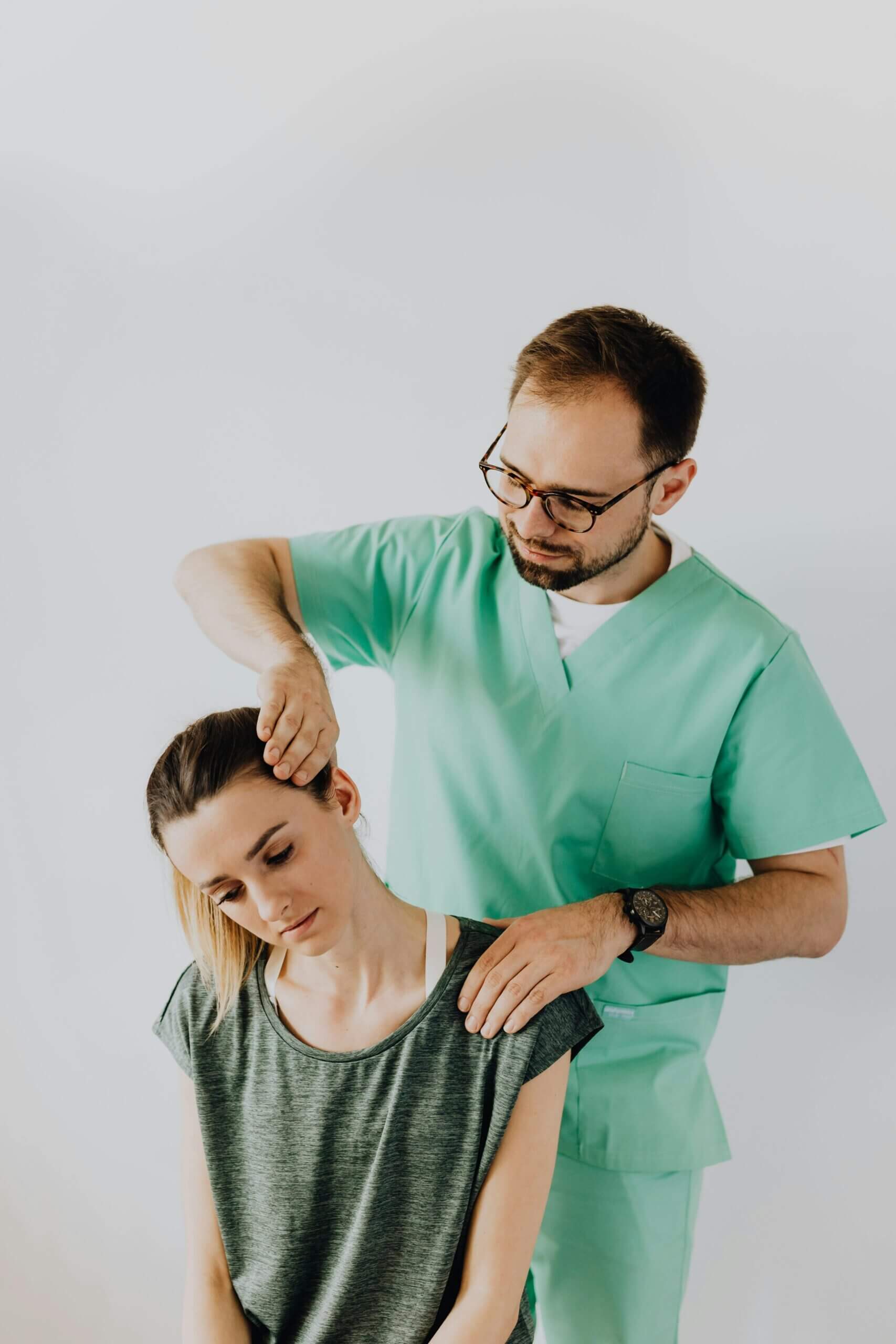 A chiropractor adjusts a patient's neck to relieve pain indoors.